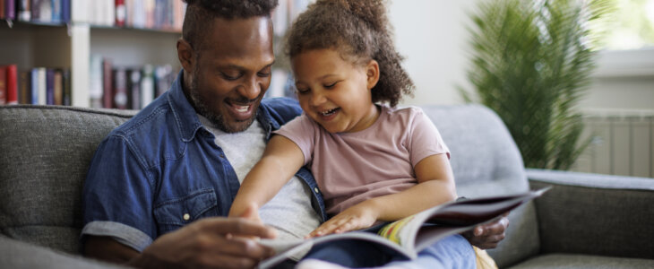 A single parent with a child reading on the couch