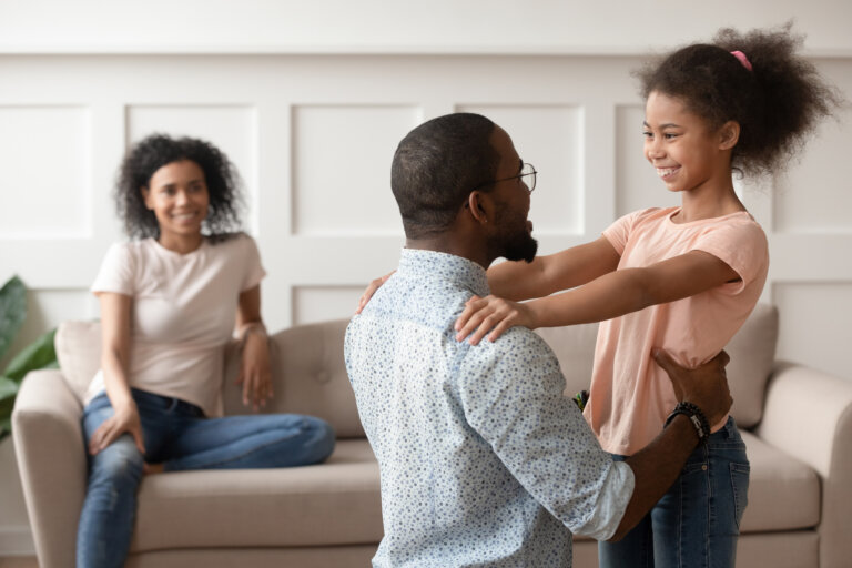 Dad embracing his daughter while her mother smiles and watches