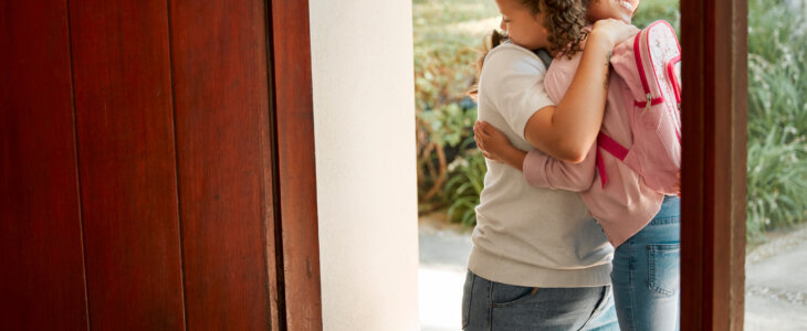 Little girl kissing her mother. Young mother hugging her daughter. Loving mother hugging daughter before school outside. Little girl going to school. Happy woman embracing daughter