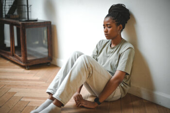 Woman looking distressed sits against a wall