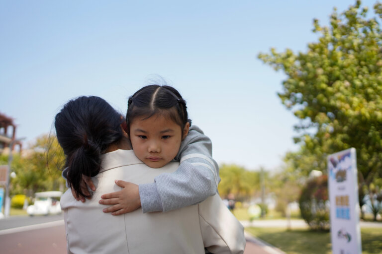 Young child embracing woman.
