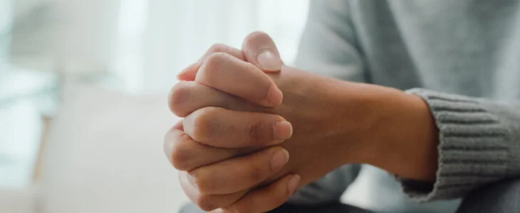 Closeup of young Asian female psychotherapist discussing a problem and touch hand young depressed sit on couch at clinic. Medical insurance, Mental health concept.
